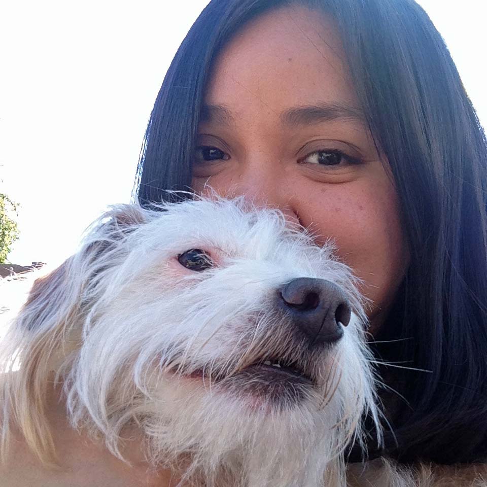 woman holding small white dog in front of her face