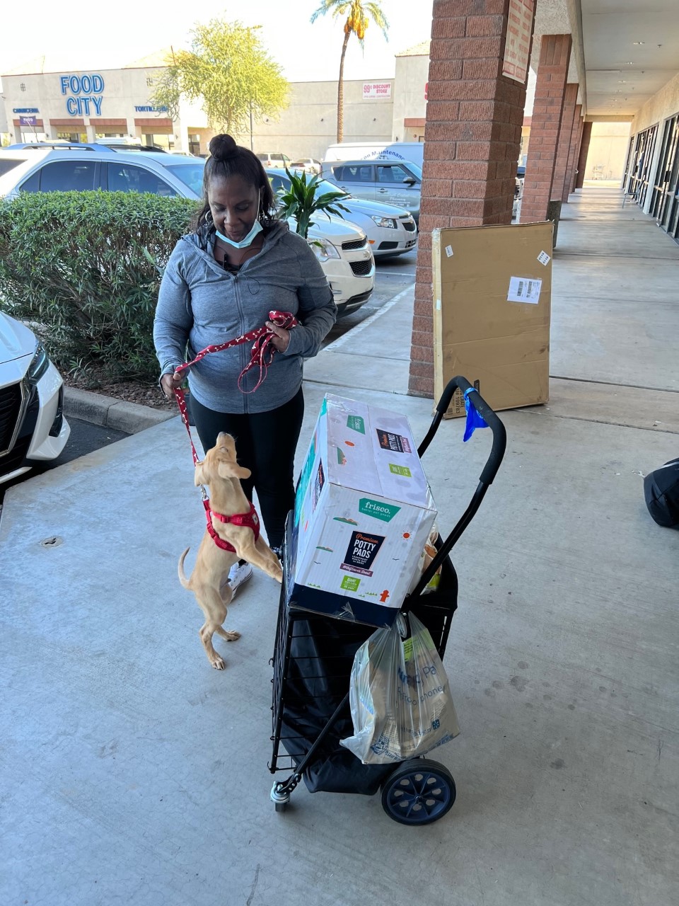 Woman standing with her dog outside of The Arizona Pet Project resource center with pet supplies