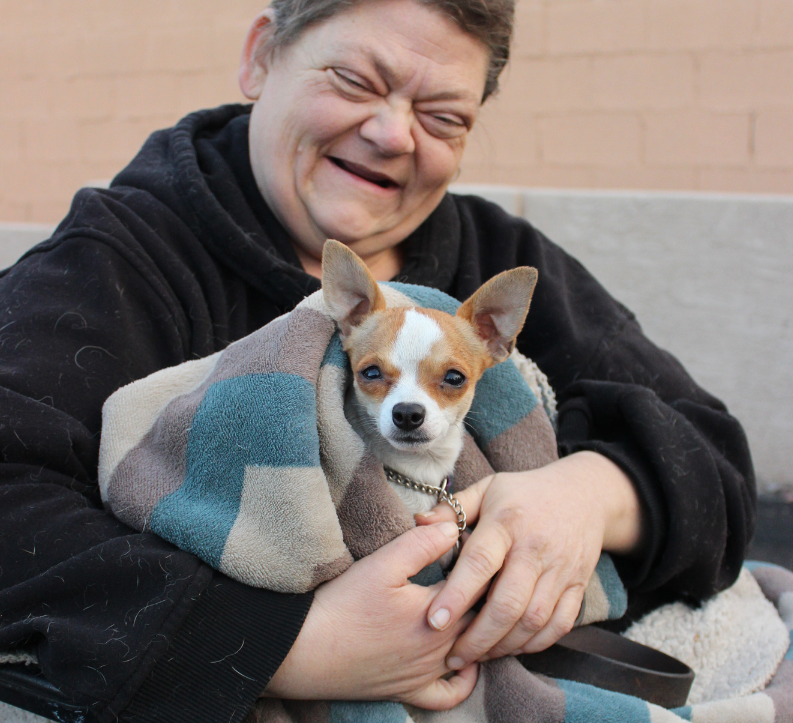 woman in wheelchair smiling holding her small dog