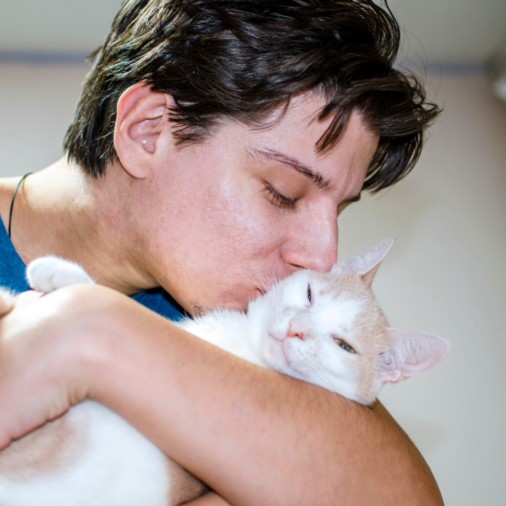 young man hugging and kissing his cat