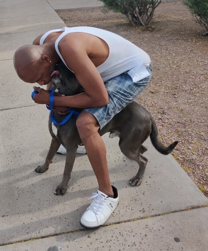 man bent over and hugging his dog