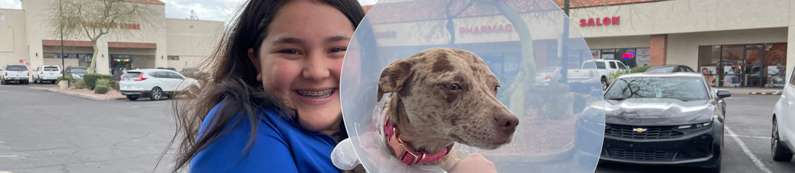Young woman smiling holding her dog wearing a surgical cone