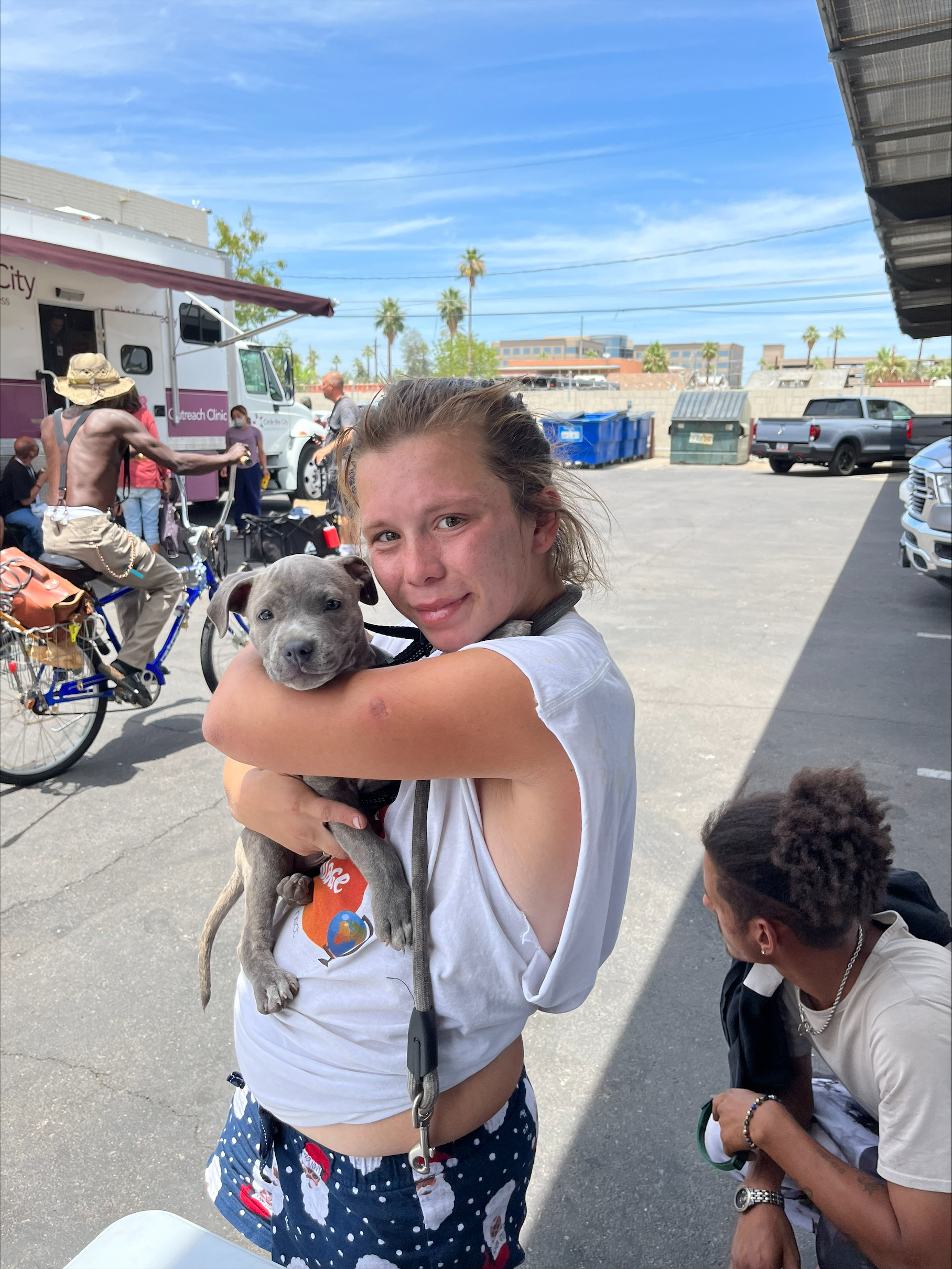 young woman holding small grey bully breed puppy in her arms